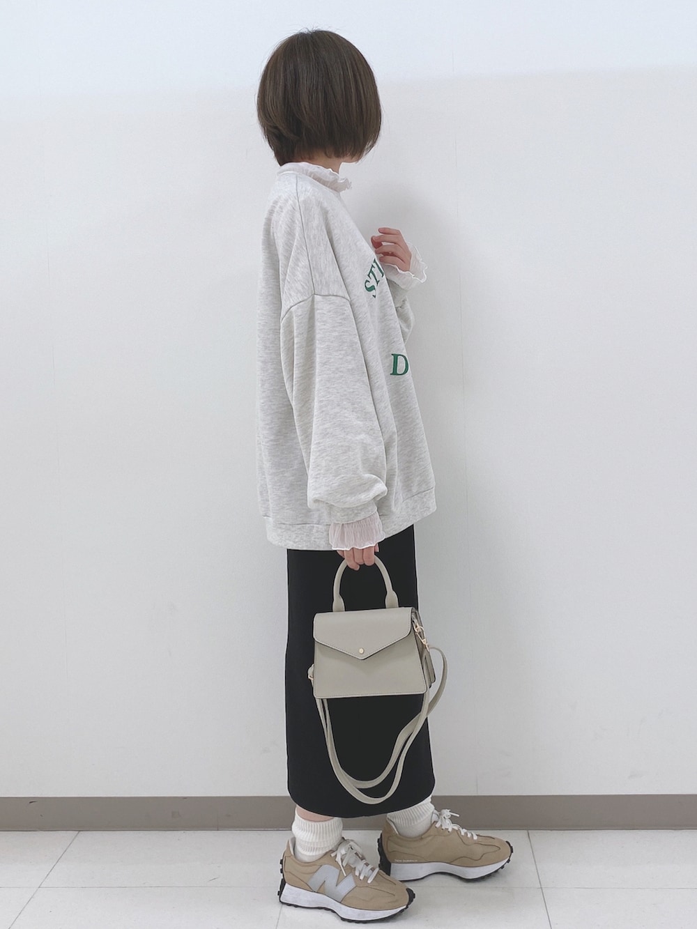 グレー系のスウェット、ホワイト系のTシャツ/カットソー、ブラック系のスカートを着用したレディースの秋コーディネートの2枚目の写真