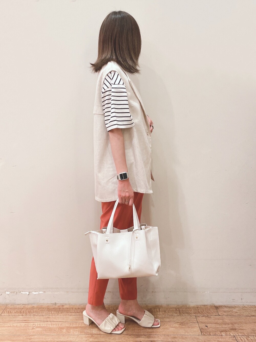 ブラック系のTシャツ/カットソー、ベージュ系のベスト、ホワイト系のショルダーバッグを着用したレディースの春コーディネートの2枚目の写真