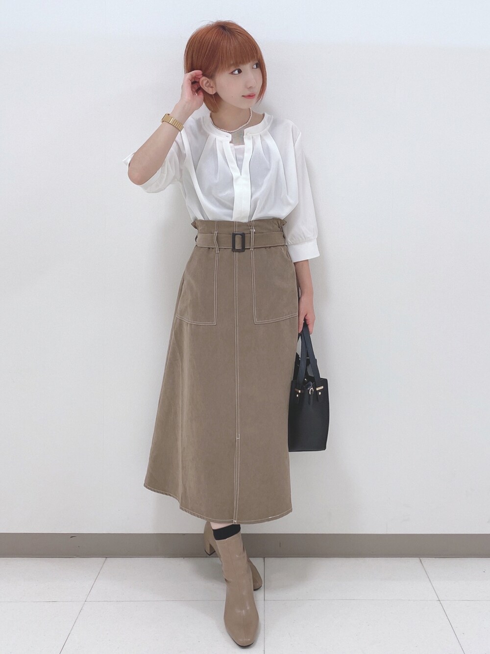 ホワイト系のTシャツ/カットソー、ベージュ系のスカート、ベージュ系のブーツを着用したレディースの秋コーディネートの4枚目の写真