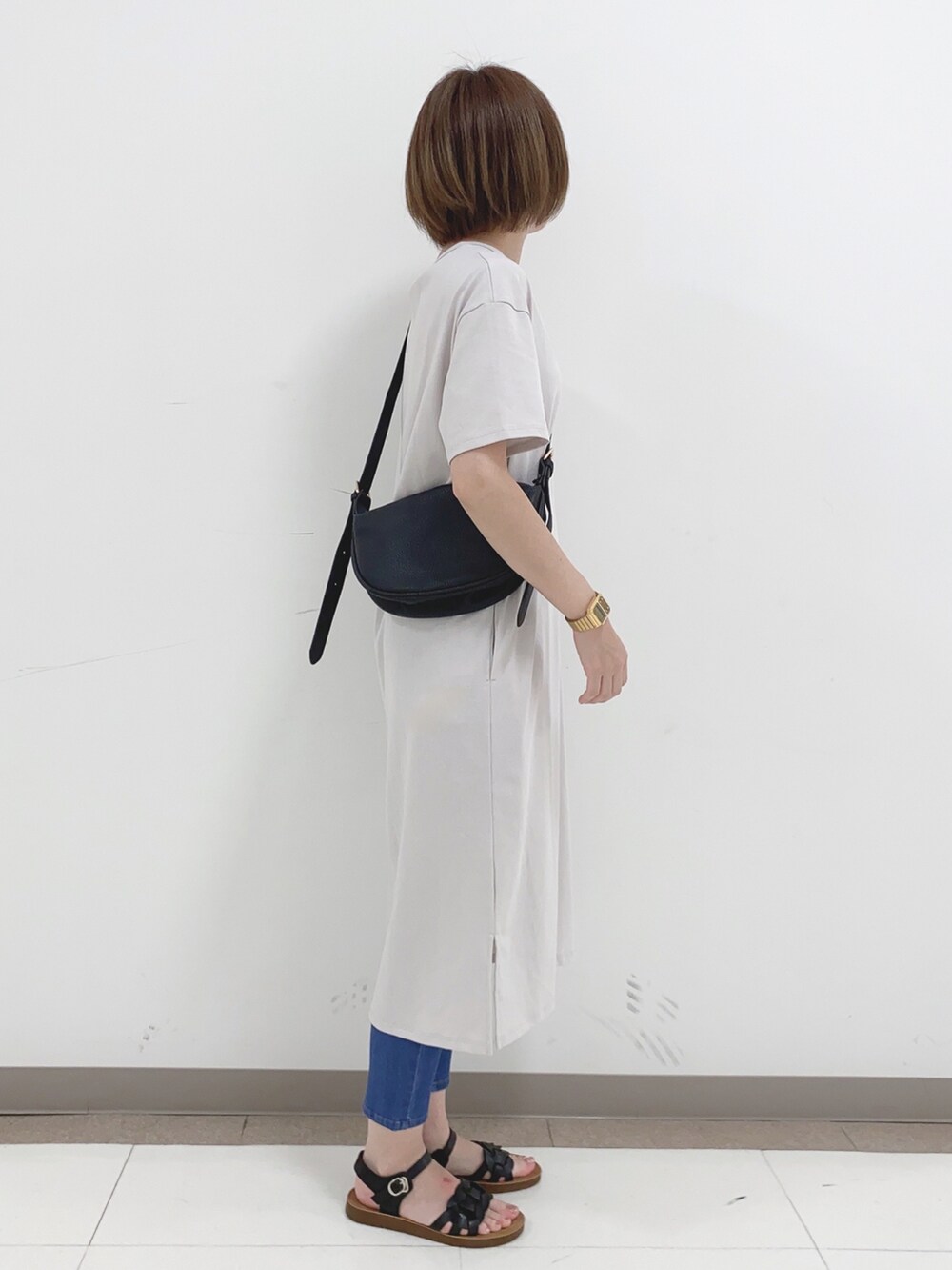 グレー系のワンピース、ブルー系のデニムパンツ、ブラック系のサンダルを着用したレディースの夏コーディネートの2枚目の写真