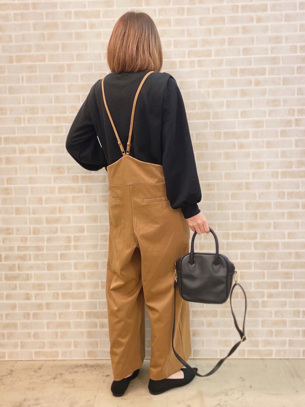 イエロー系のサロペット/オーバーオール、ブラック系のTシャツ/カットソー、ブラック系のショルダーバッグを着用したレディースの冬コーディネートの3枚目の写真