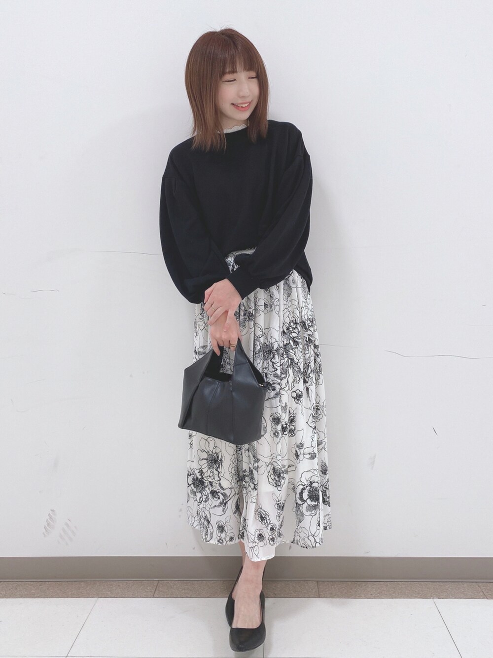 ブラック系のスウェット、ホワイト系のスカート、ブラック系のパンプスを着用したレディースの春コーディネートの4枚目の写真