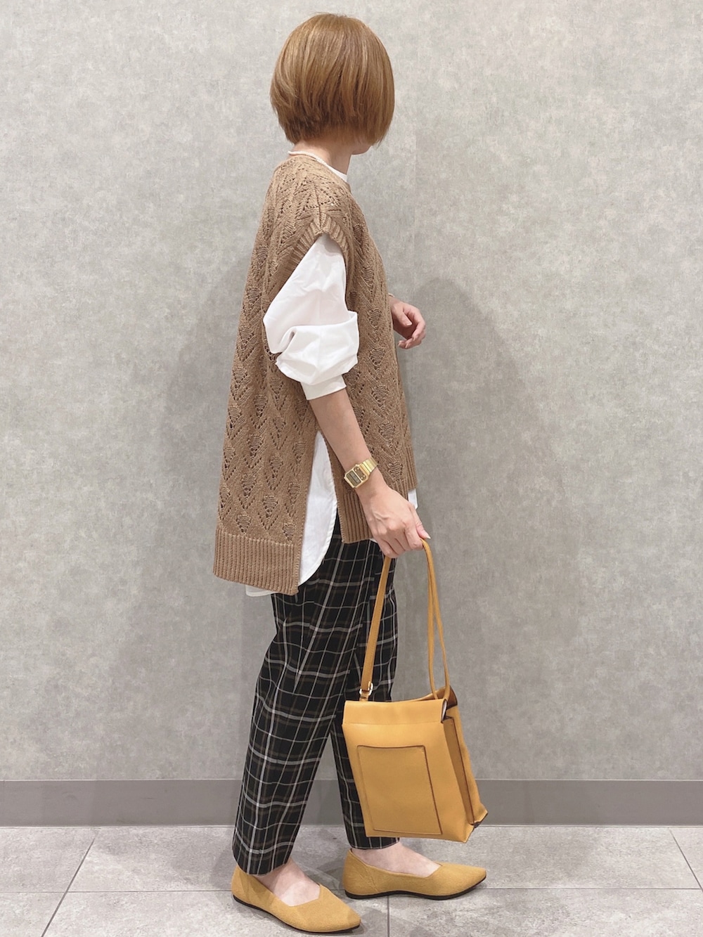 イエロー系のベスト、ホワイト系のシャツ/ブラウス、ブラック系のパンツを着用したレディースの夏コーディネートの2枚目の写真