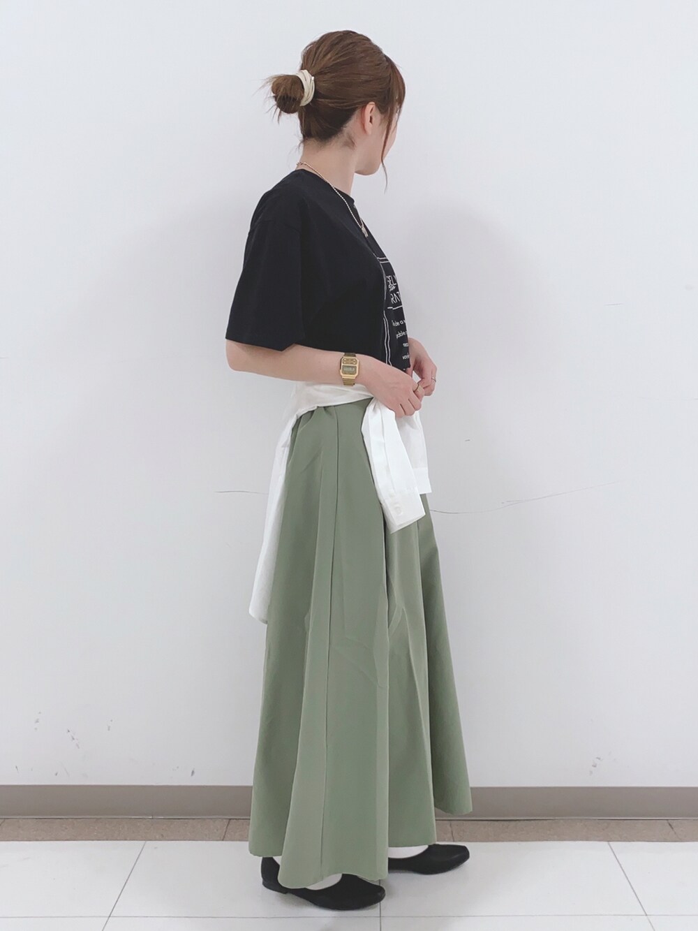 ブラック系のTシャツ/カットソー、グリーン系のスカート、ホワイト系のシャツ/ブラウスを着用したレディースの春コーディネートの2枚目の写真
