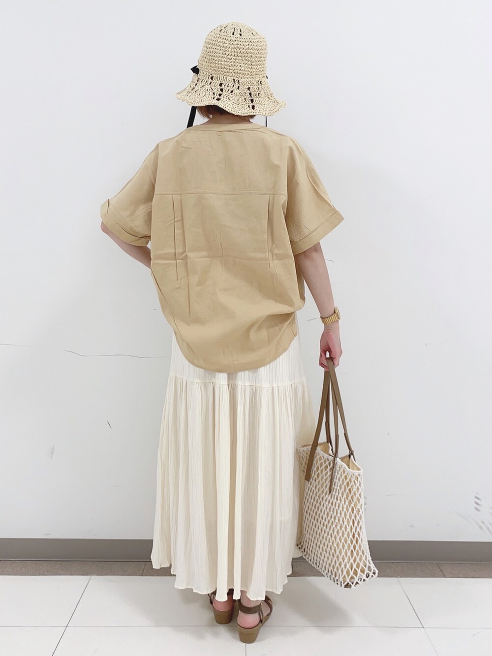イエロー系のシャツ/ブラウス、ホワイト系のスカート、ホワイト系のトートバッグを着用したレディースの夏コーディネートの3枚目の写真