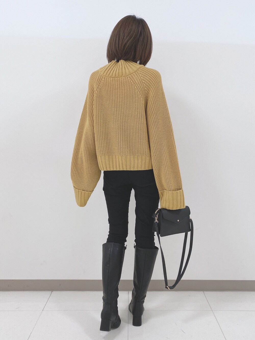 イエロー系のニット/セーター、ブラック系のその他パンツ、ブラック系のブーツを着用したレディースの冬コーディネートの3枚目の写真