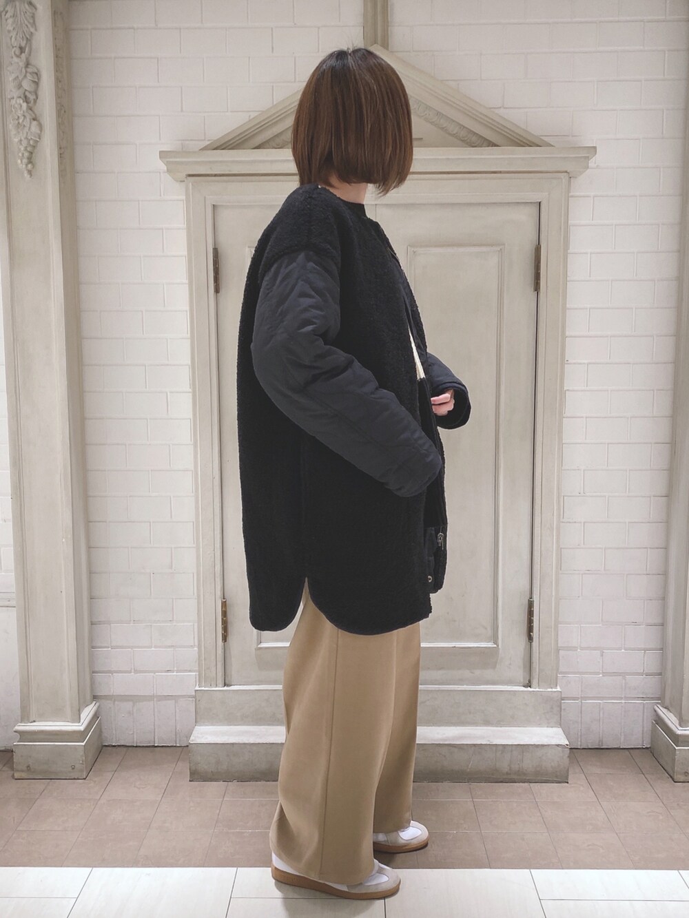 ブラック系のノーカラージャケット、ブラック系のニット/セーター、ベージュ系のその他パンツを着用したレディースの冬コーディネートの2枚目の写真