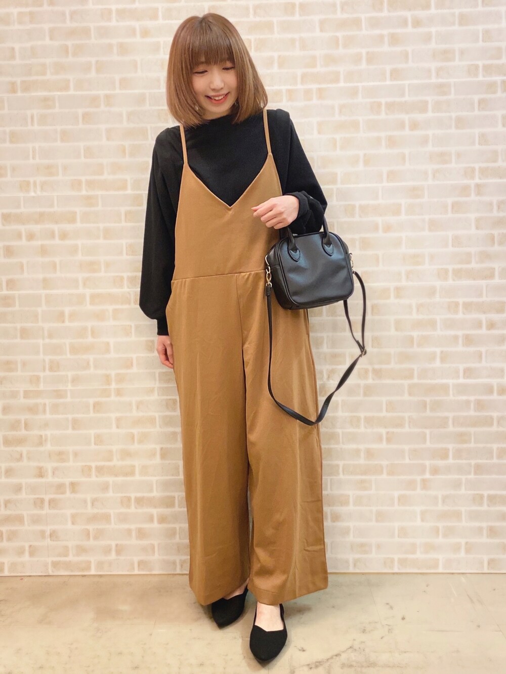 イエロー系のサロペット/オーバーオール、ブラック系のTシャツ/カットソー、ブラック系のショルダーバッグを着用したレディースの冬コーディネートの2枚目の写真