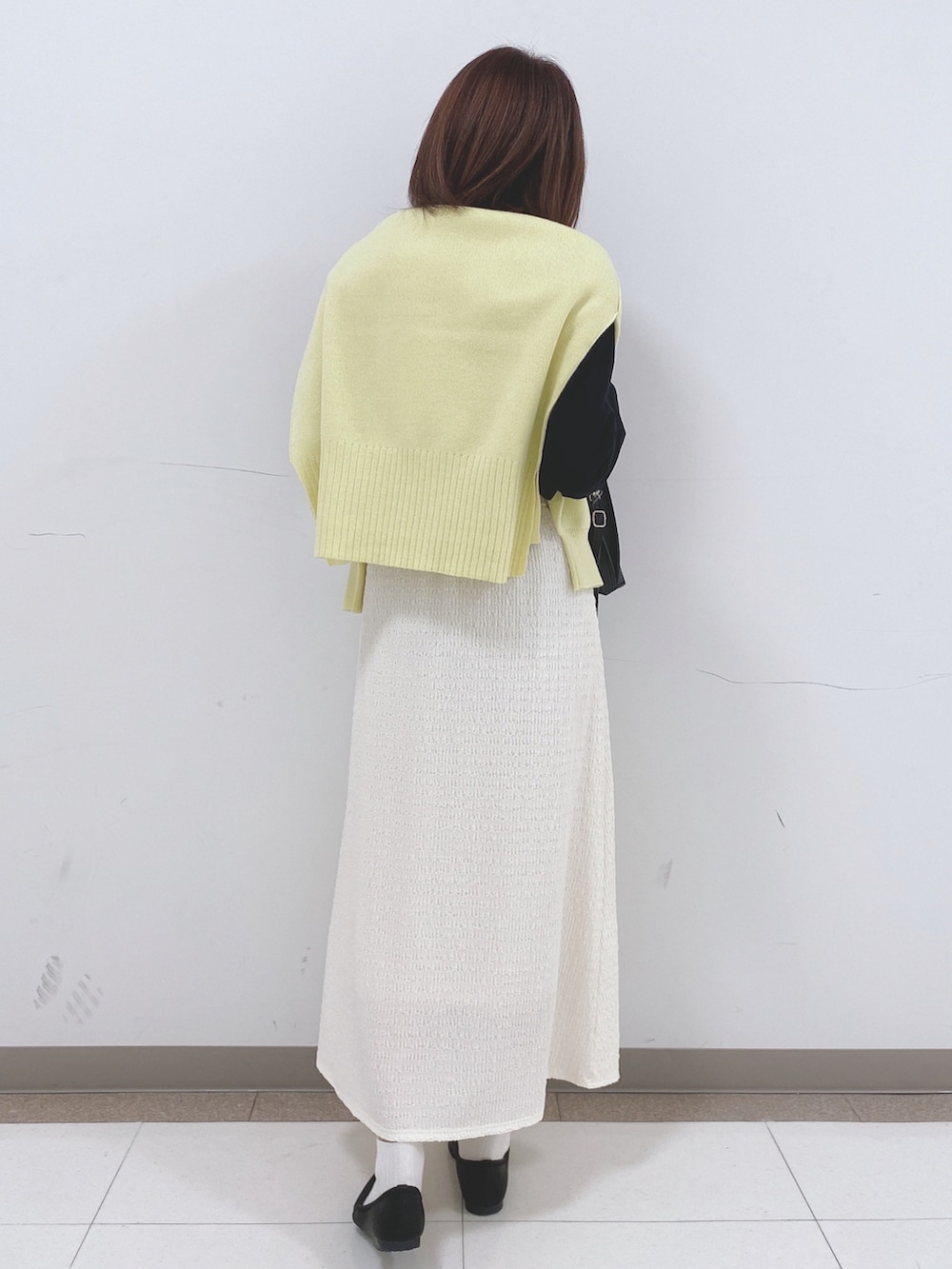 ブラック系のTシャツ/カットソー、イエロー系のニット/セーター、ブラック系のパンプスを着用したレディースの冬コーディネートの3枚目の写真