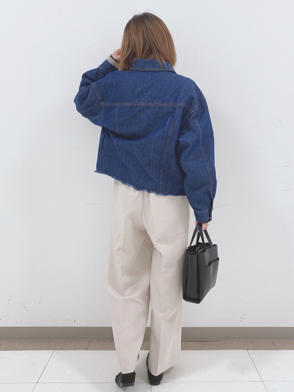 ブルー系のデニムジャケット、ベージュ系のニット/セーター、ベージュ系のその他パンツを着用したレディースの春コーディネートの3枚目の写真