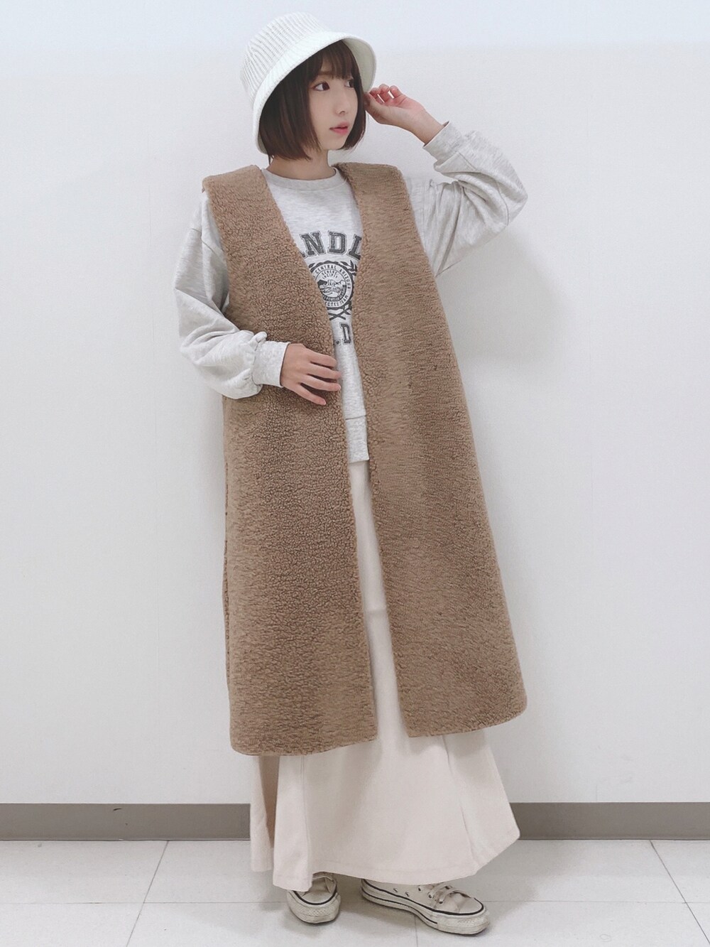 イエロー系のベスト、グレー系のスウェット、ホワイト系のスカートを着用したレディースの秋コーディネートの4枚目の写真