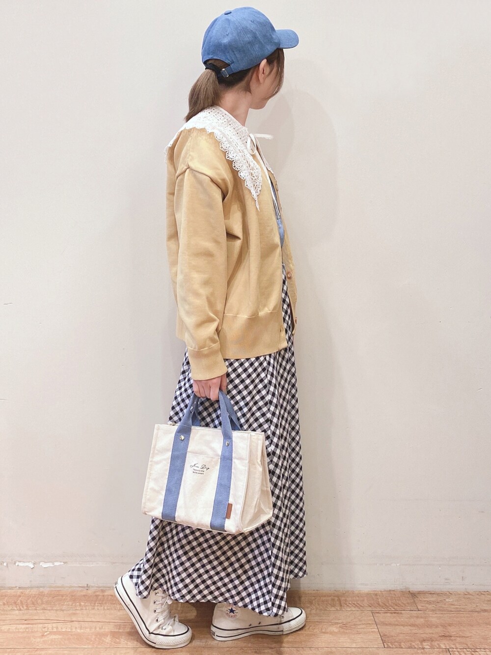 ホワイト系のTシャツ/カットソー、イエロー系のニット/セーター、ブラック系のスカートを着用したレディースの春コーディネートの2枚目の写真