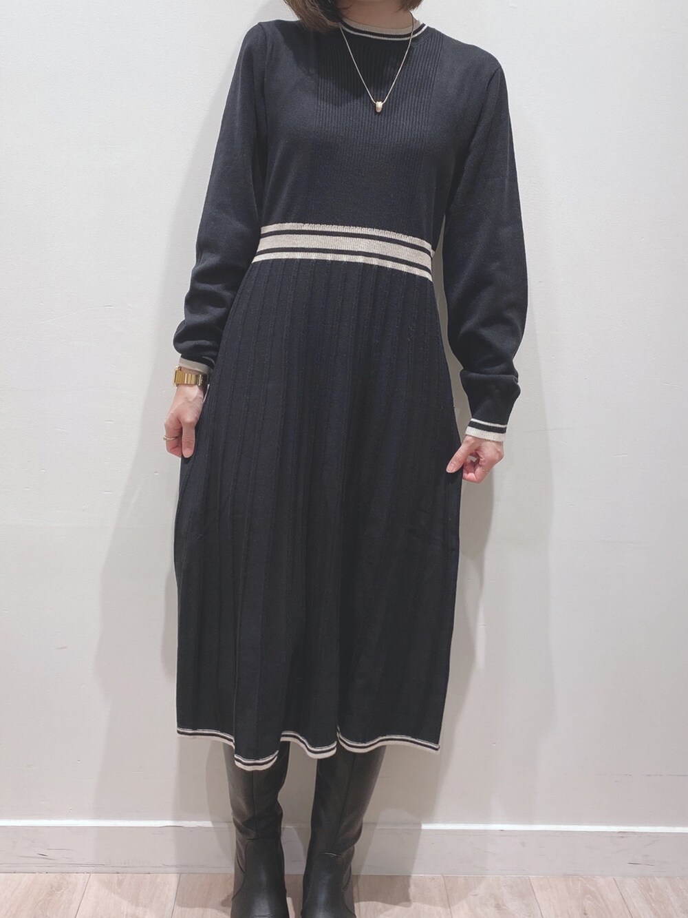 ベージュ系のノーカラーコート、ブラック系のワンピース、ブラック系のブーツを着用したレディースの冬コーディネートの5枚目の写真