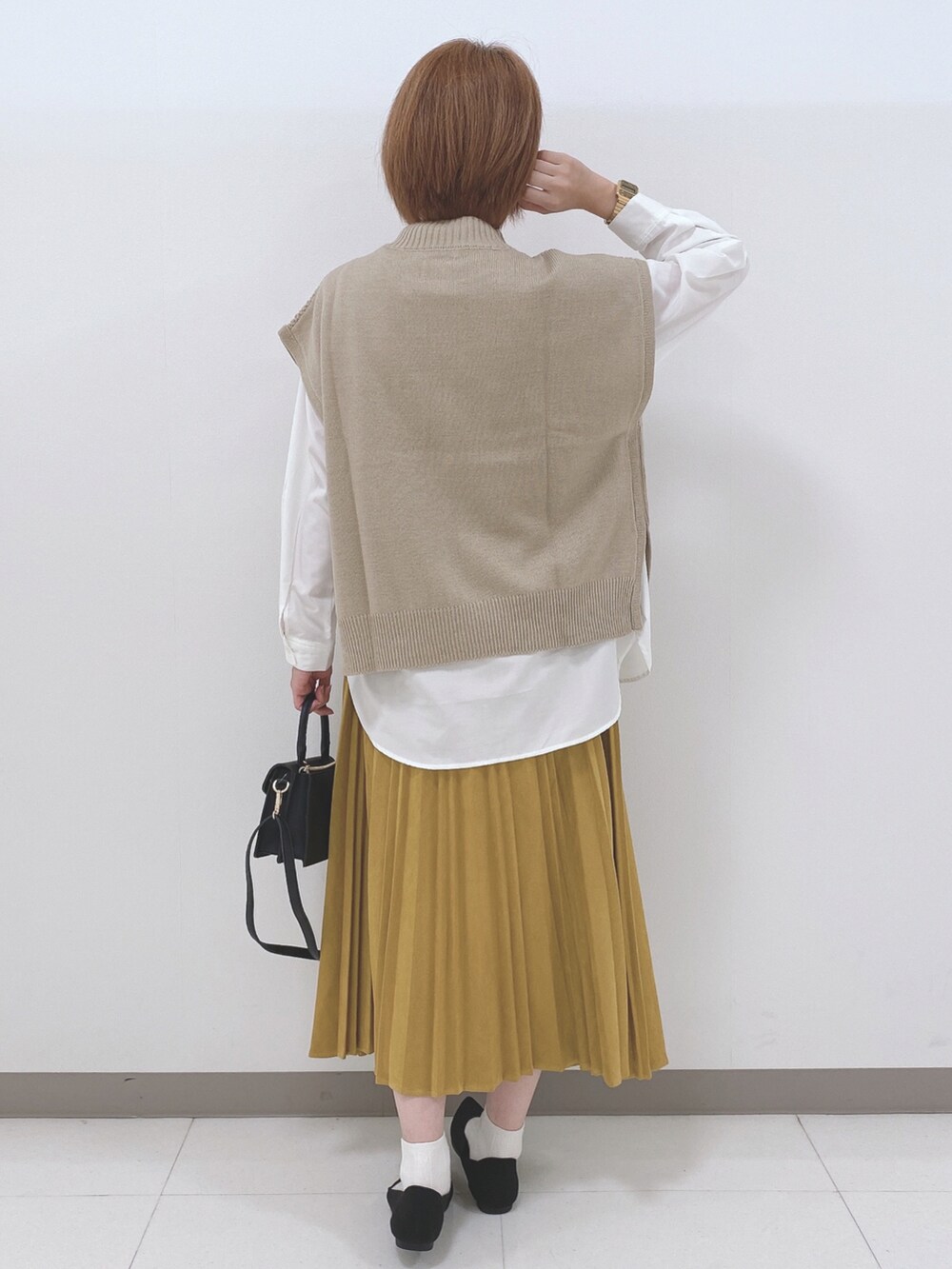 ベージュ系のベスト、ホワイト系のシャツ/ブラウス、イエロー系のスカートを着用したレディースの秋コーディネートの3枚目の写真