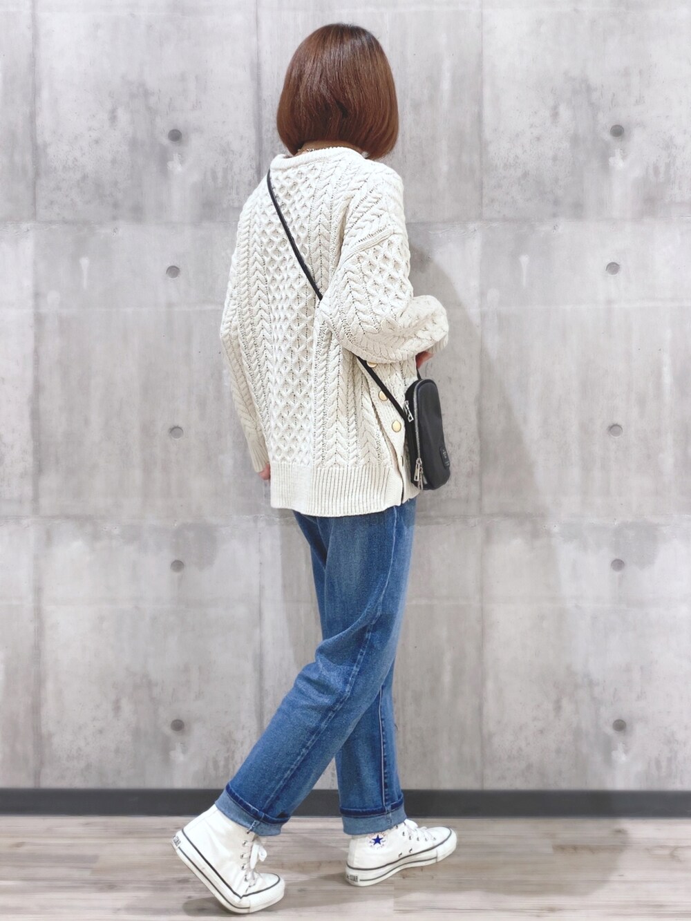 ホワイト系のニット/セーター、ブラック系のショルダーバッグ、ブルー系のデニムパンツを着用したレディースの冬コーディネートの2枚目の写真