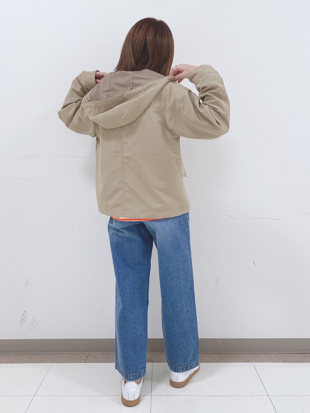 オレンジ系のTシャツ/カットソー、ベージュ系のブルゾン、ブルー系のデニムパンツを着用したレディースの春コーディネートの3枚目の写真