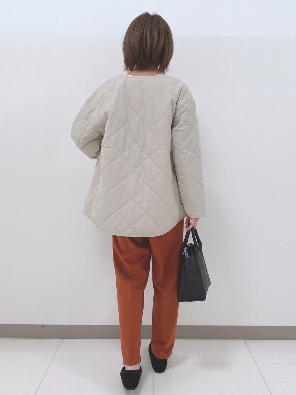 グレー系のブルゾン、ホワイト系のニット/セーター、オレンジ系のその他パンツを着用したレディースの秋コーディネートの3枚目の写真