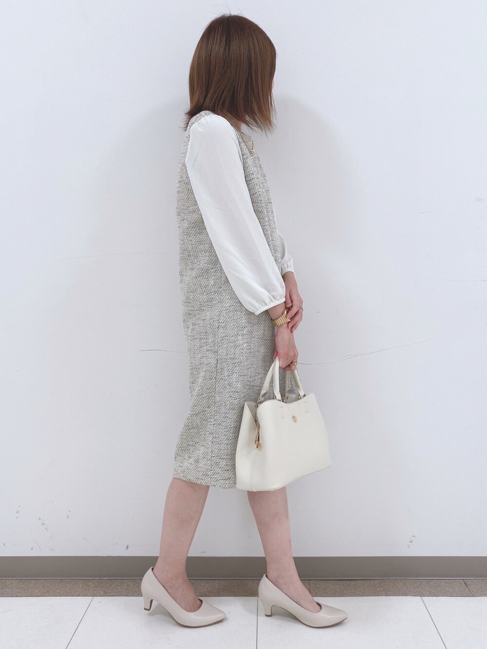 グレー系のワンピース、ベージュ系のパンプス、ホワイト系のトートバッグを着用したレディースの春コーディネートの2枚目の写真