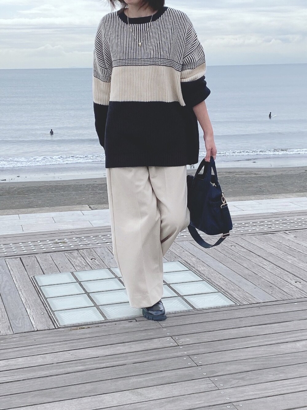 ブラック系のニット/セーター、ホワイト系のパンツ、ブラック系のトートバッグを着用したレディースの冬コーディネートの3枚目の写真