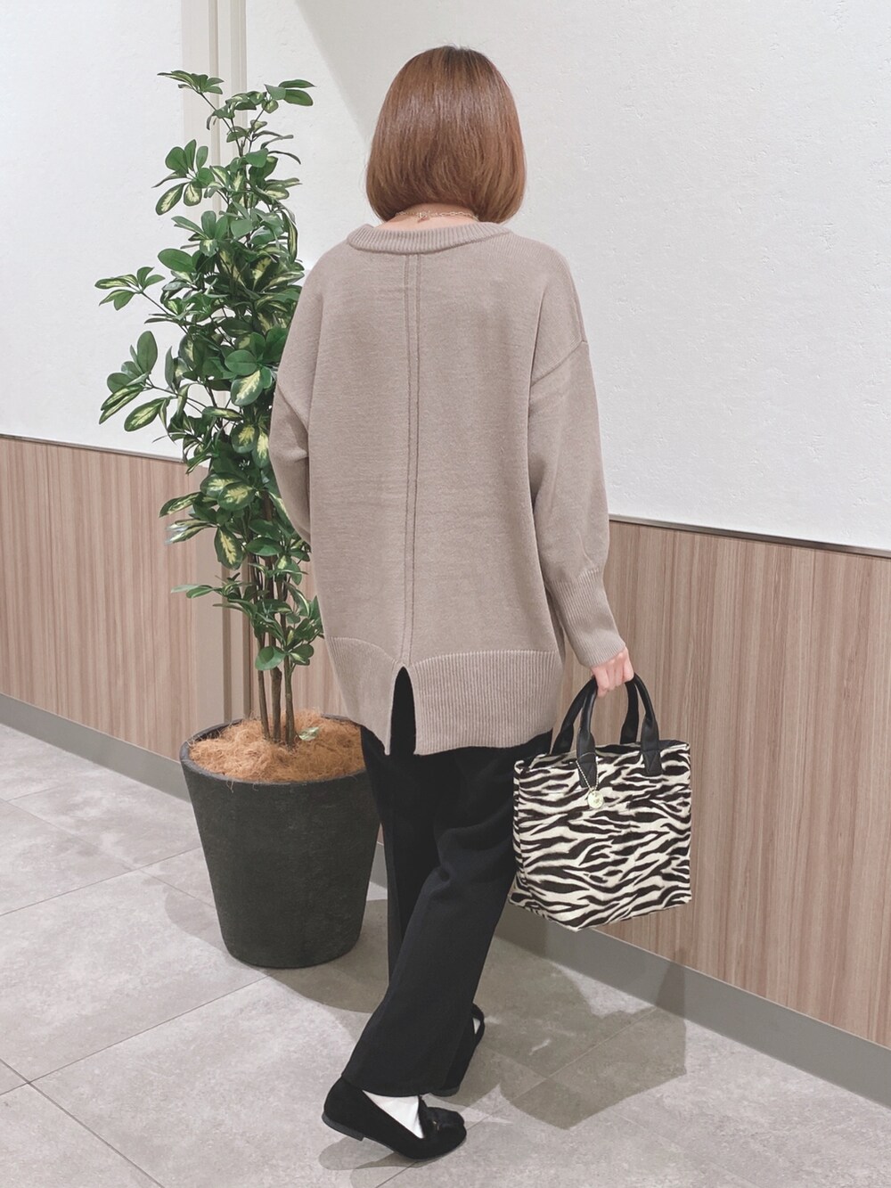 ベージュ系のニット/セーター、ブラック系のトートバッグ、ブラック系のドレスシューズを着用したレディースの秋コーディネートの2枚目の写真