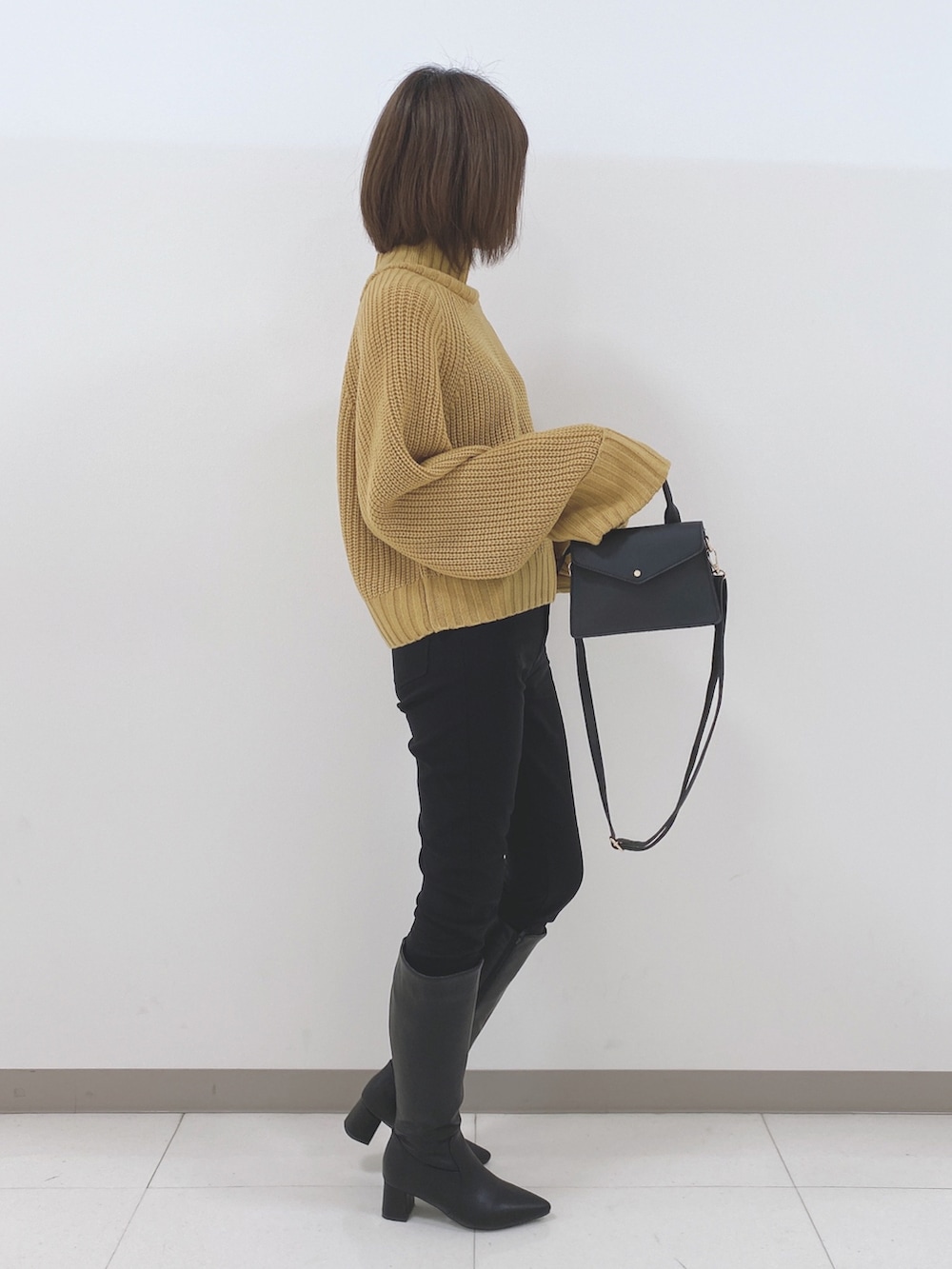 イエロー系のニット/セーター、ブラック系のその他パンツ、ブラック系のブーツを着用したレディースの冬コーディネートの2枚目の写真