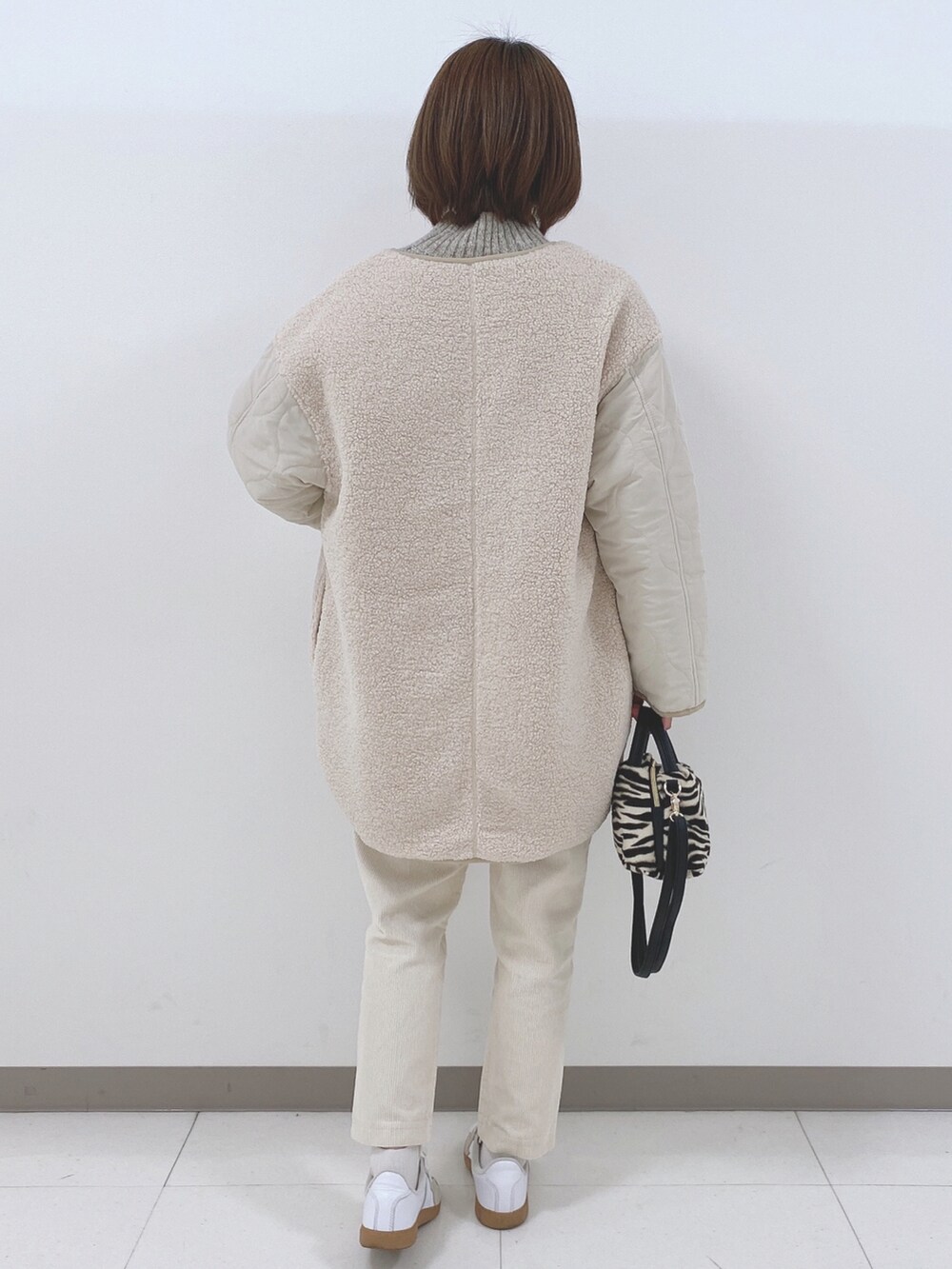 ベージュ系のノーカラージャケット、ベージュ系のニット/セーター、ホワイト系のスニーカーを着用したレディースの秋コーディネートの3枚目の写真