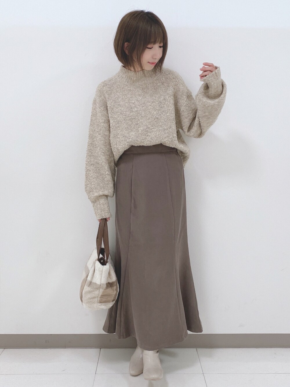 ベージュ系のニット/セーター、ブラウン系のスカート、ホワイト系のブーツを着用したレディースの秋コーディネートの4枚目の写真