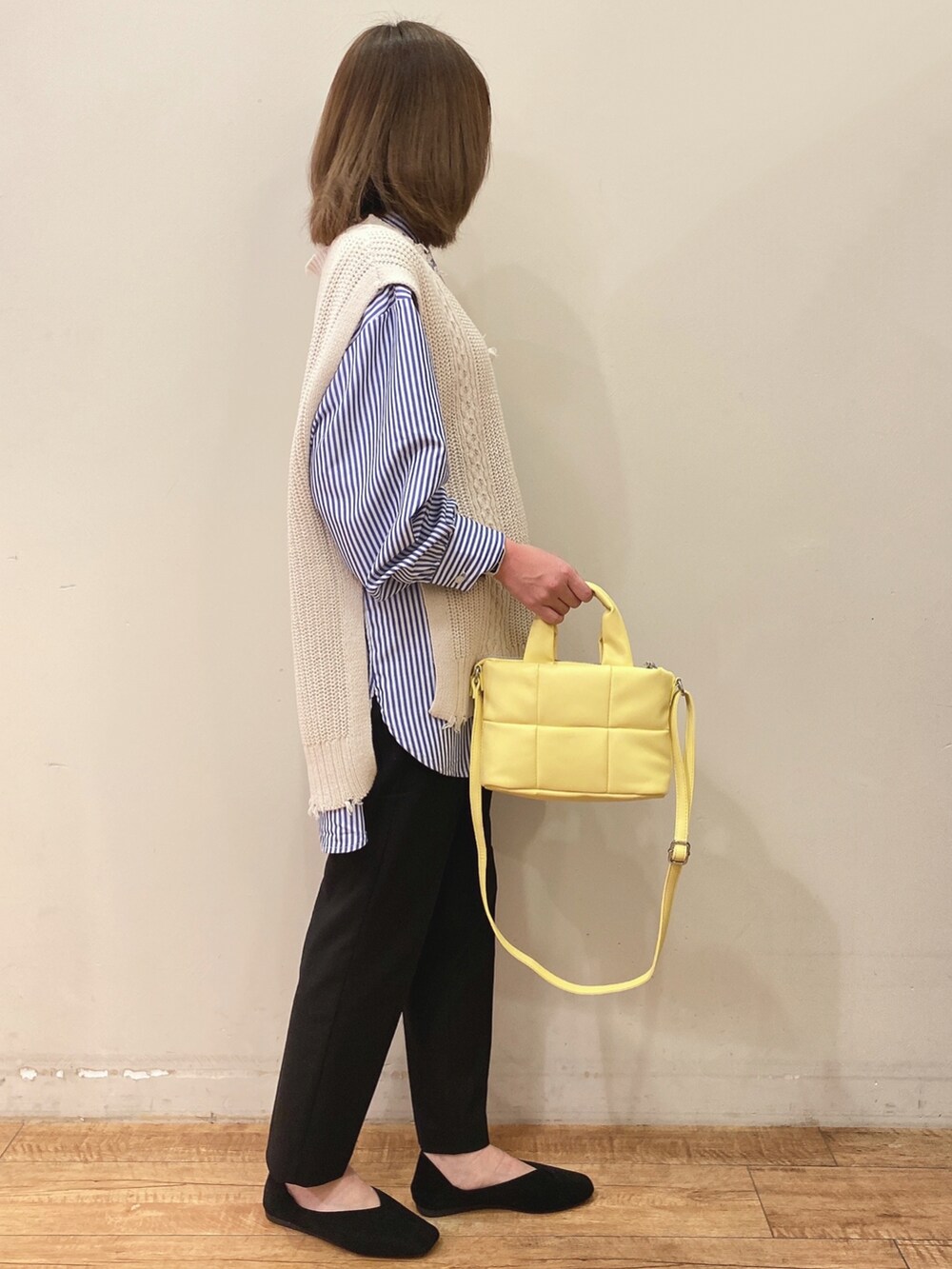 ホワイト系のベスト、ブルー系のワンピース、ブラック系のパンツを着用したレディースの春コーディネートの2枚目の写真