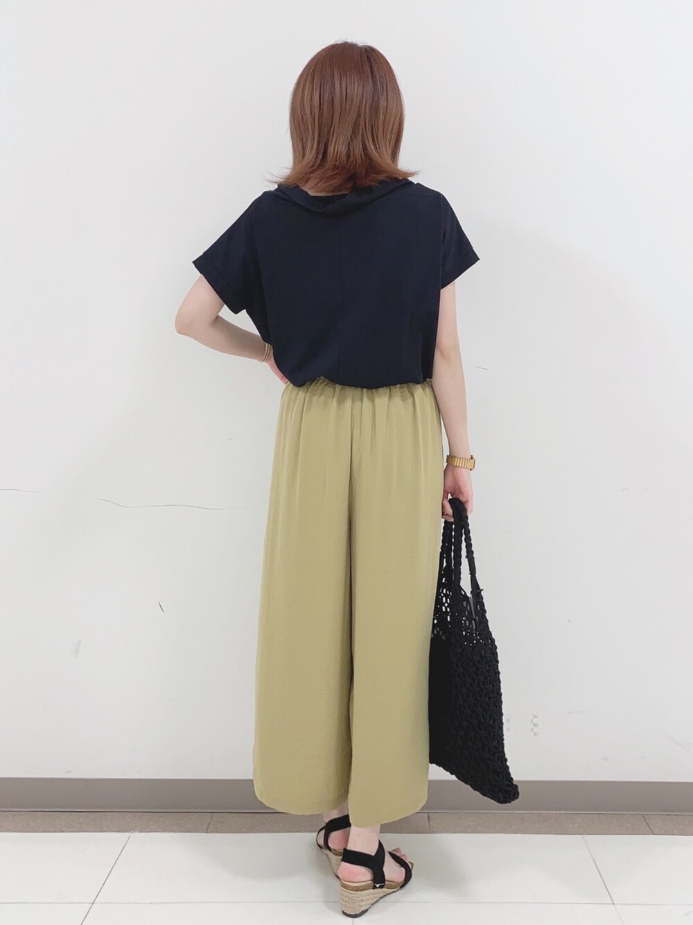 ブラック系のTシャツ/カットソー、イエロー系のその他パンツ、ブラック系のサンダルを着用したレディースの春コーディネートの3枚目の写真