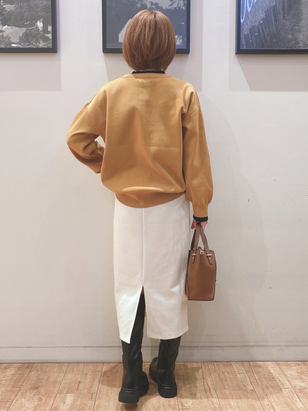 ブラック系のブーツ、イエロー系のカーディガン/ボレロ、ホワイト系のスカートを着用したレディースの秋コーディネートの3枚目の写真