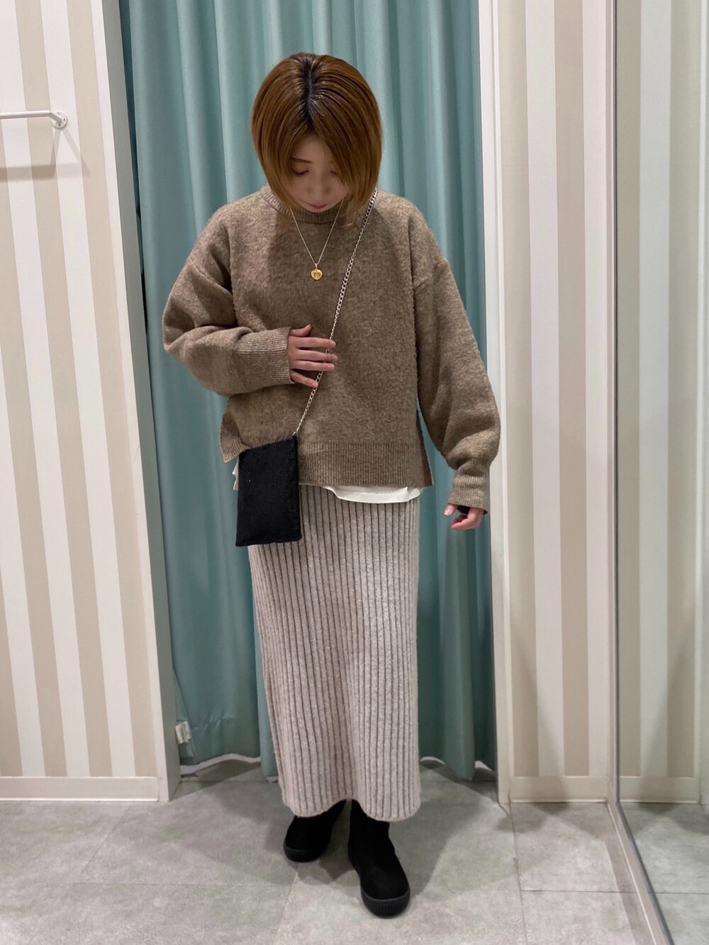 イエロー系のニット/セーター、ホワイト系のTシャツ/カットソー、ベージュ系のスカートを着用したレディースの冬コーディネートの4枚目の写真