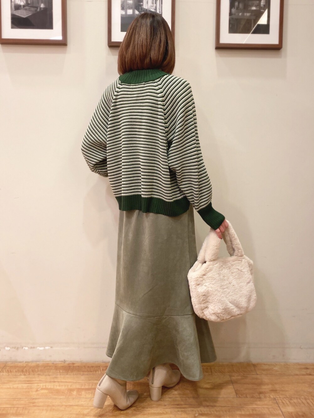 グリーン系のニット/セーター、グリーン系のスカート、ホワイト系のブーツを着用したレディースの冬コーディネートの4枚目の写真