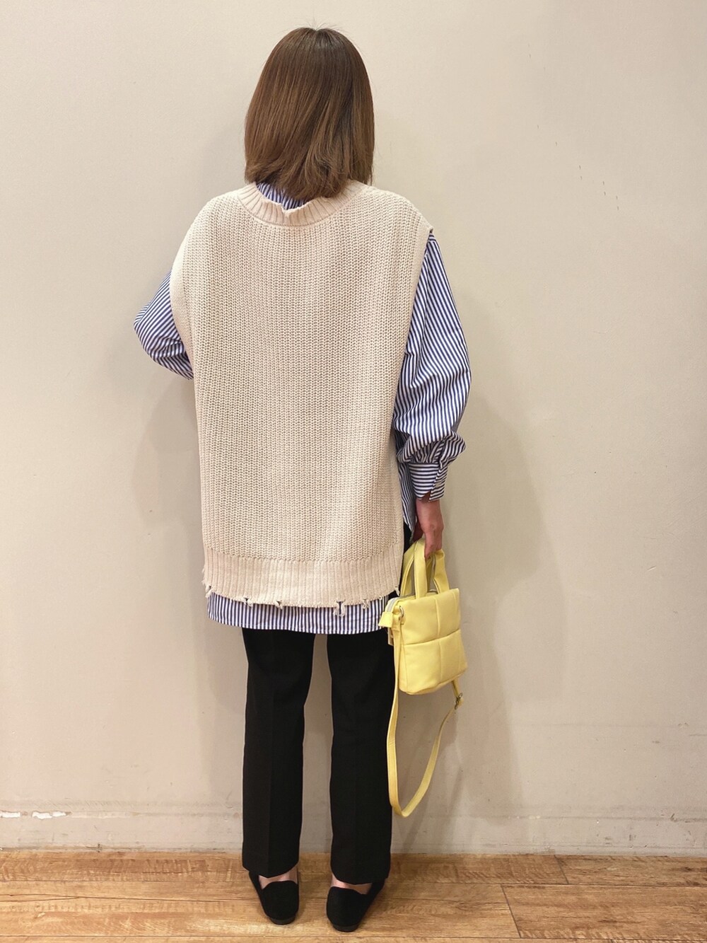 ホワイト系のベスト、ブルー系のワンピース、ブラック系のパンツを着用したレディースの春コーディネートの3枚目の写真