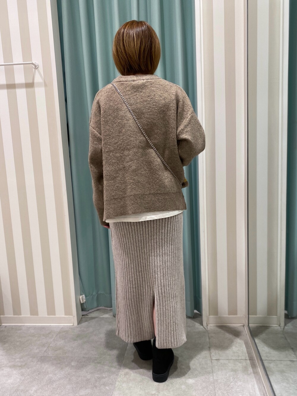 イエロー系のニット/セーター、ホワイト系のTシャツ/カットソー、ベージュ系のスカートを着用したレディースの冬コーディネートの3枚目の写真