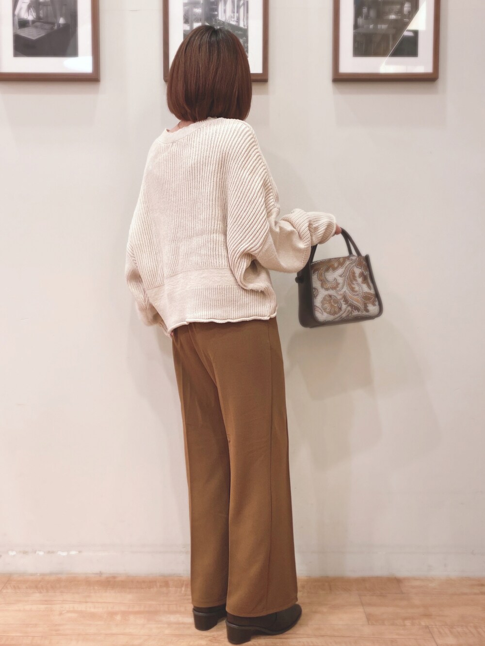 ベージュ系のニット/セーター、ブラウン系のトートバッグ、ブラウン系のブーツを着用したレディースの秋コーディネートの2枚目の写真