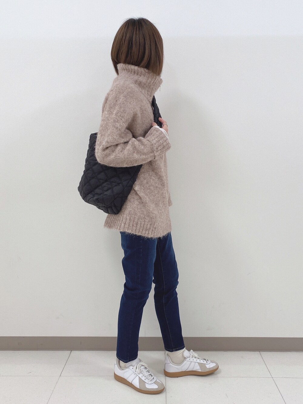 ベージュ系のニット/セーター、ブラック系のショルダーバッグ、ブルー系のデニムパンツを着用したレディースの冬コーディネートの2枚目の写真