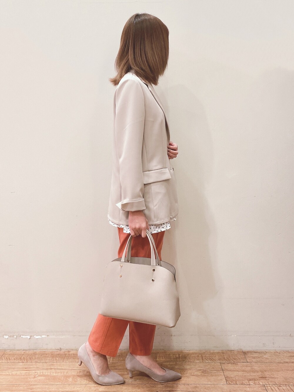 ベージュ系のテーラードジャケット、グレー系のトートバッグ、オレンジ系のその他パンツを着用したレディースの春コーディネートの2枚目の写真