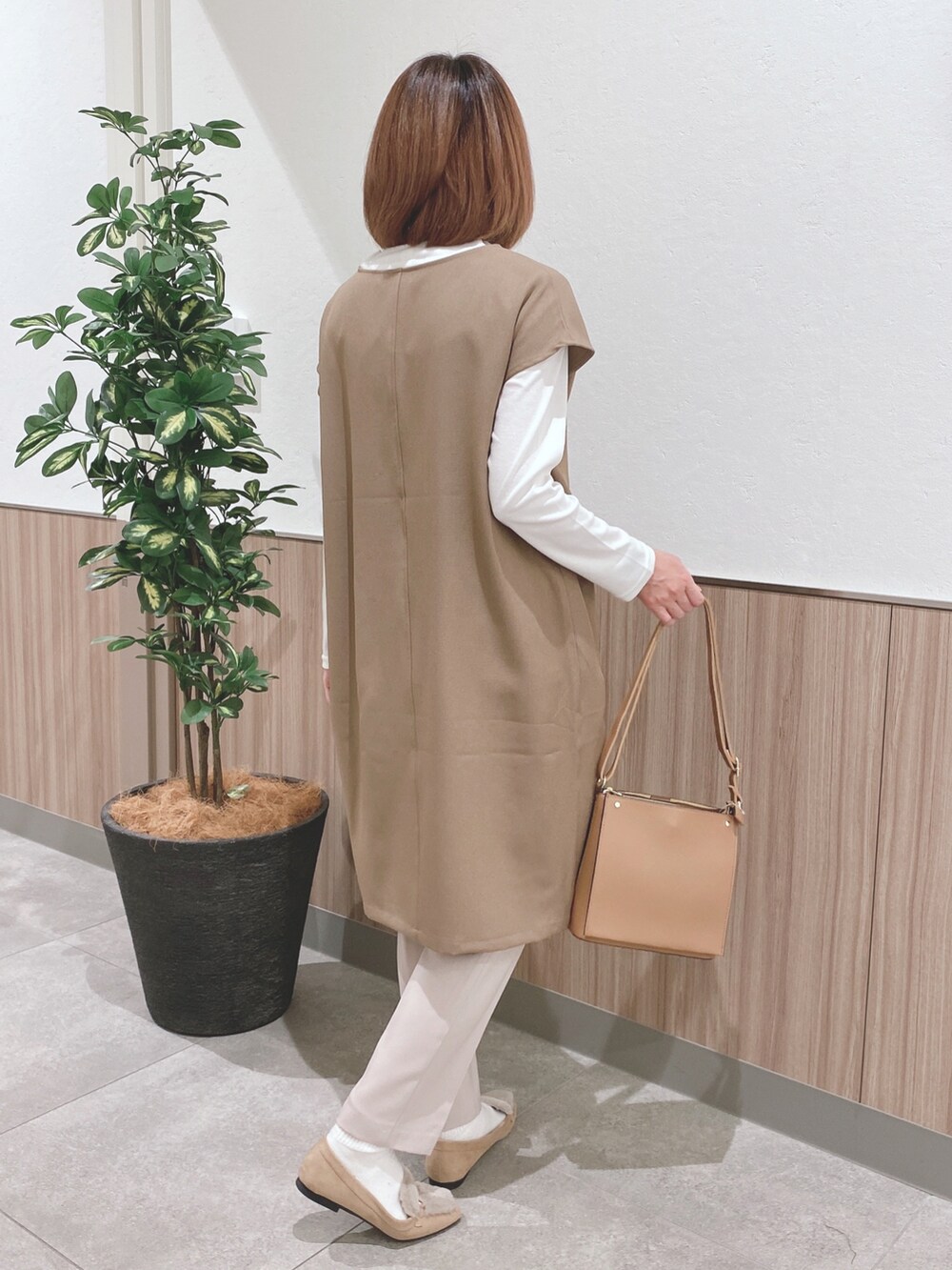 ベージュ系のスカート、ブラウン系のショルダーバッグ、ベージュ系のドレスシューズを着用したレディースの冬コーディネートの2枚目の写真