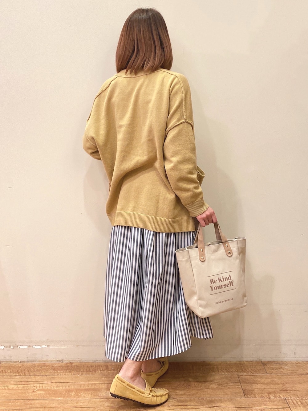 ホワイト系のTシャツ/カットソー、イエロー系のカーディガン/ボレロ、ブルー系のスカートを着用したレディースの冬コーディネートの3枚目の写真