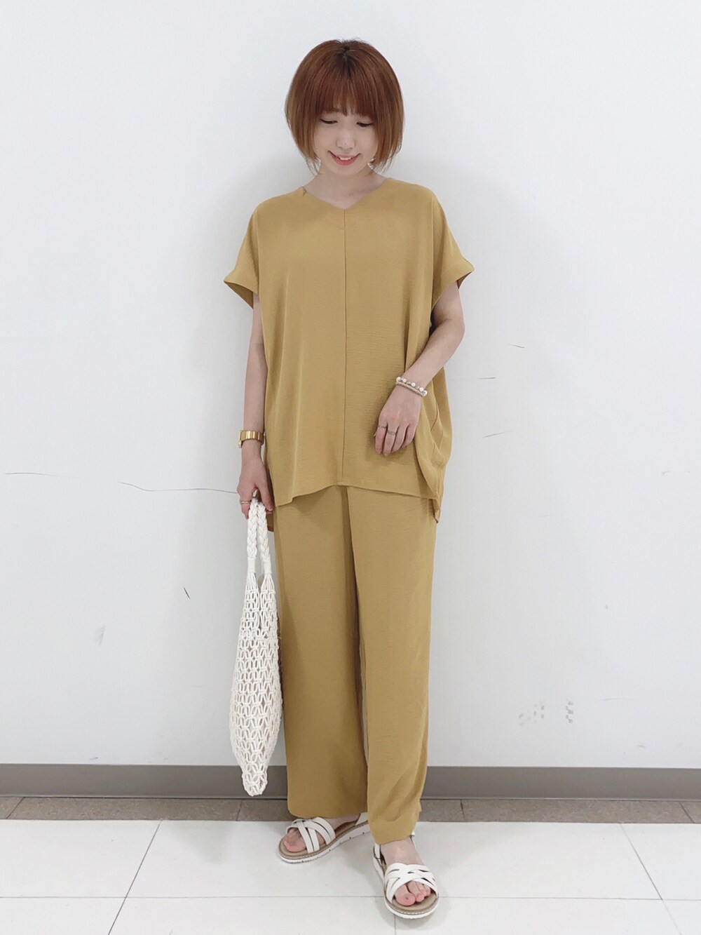 ホワイト系のトートバッグ、ホワイト系のサンダル、イエロー系のチュニックを着用したレディースの夏コーディネートの5枚目の写真