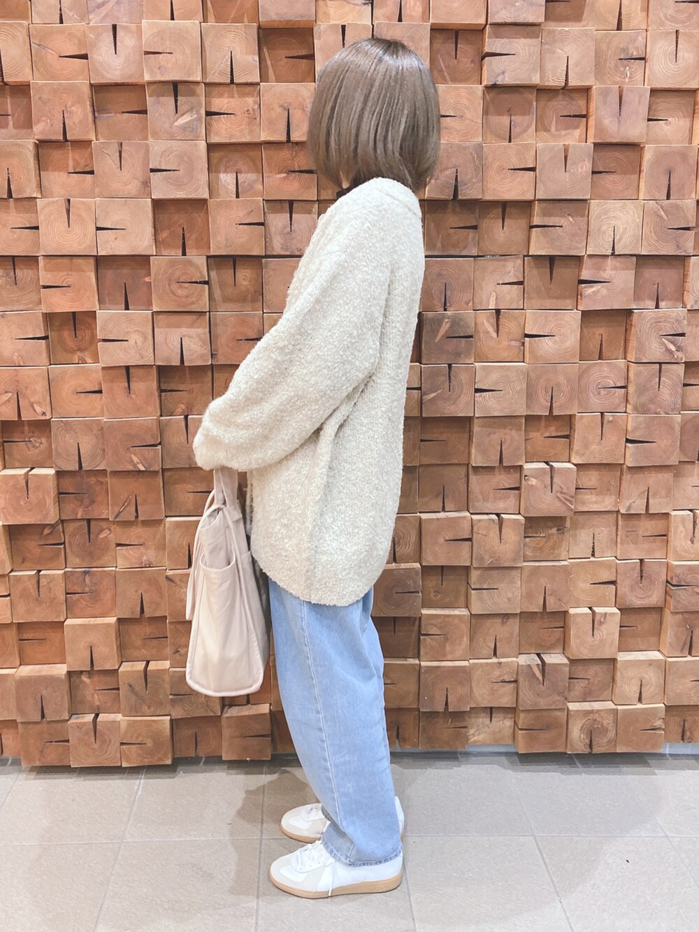 ベージュ系のカーディガン/ボレロ、ブラック系のニット/セーター、ブルー系のデニムパンツを着用したレディースの冬コーディネートの2枚目の写真