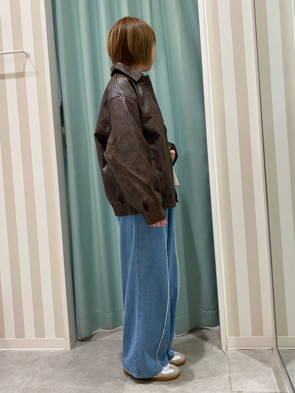 ブラウン系のブルゾン、ベージュ系のニット/セーター、ブルー系のその他パンツを着用したレディースの秋コーディネートの2枚目の写真