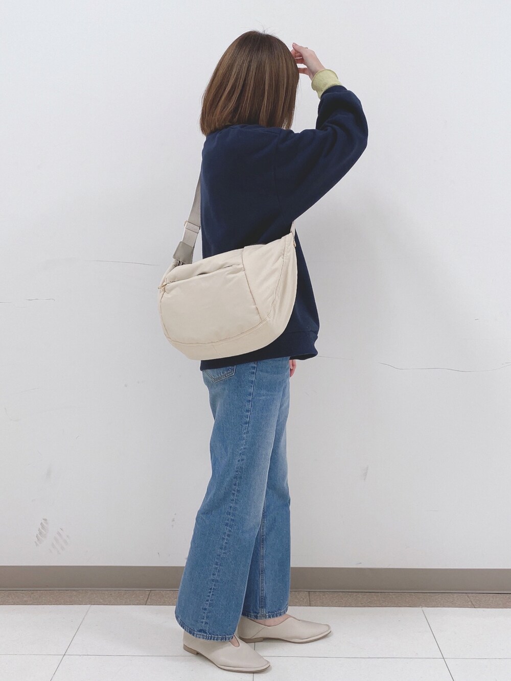 ブルー系のスウェット、ホワイト系のパンプス、ベージュ系のショルダーバッグを着用したレディースの冬コーディネートの2枚目の写真