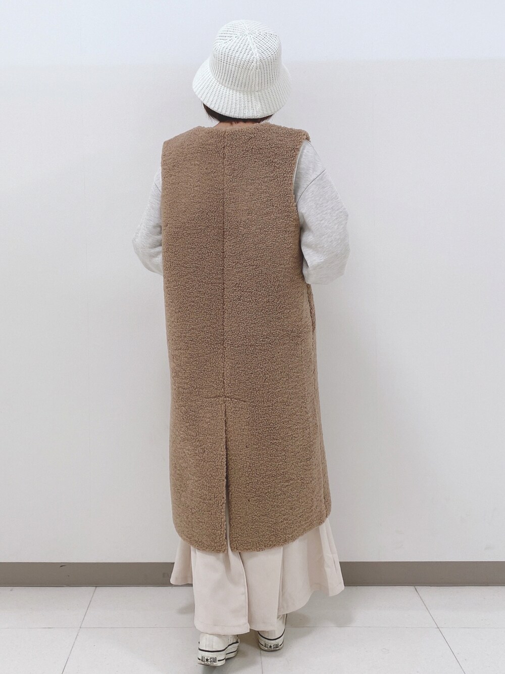 イエロー系のベスト、グレー系のスウェット、ホワイト系のスカートを着用したレディースの秋コーディネートの3枚目の写真