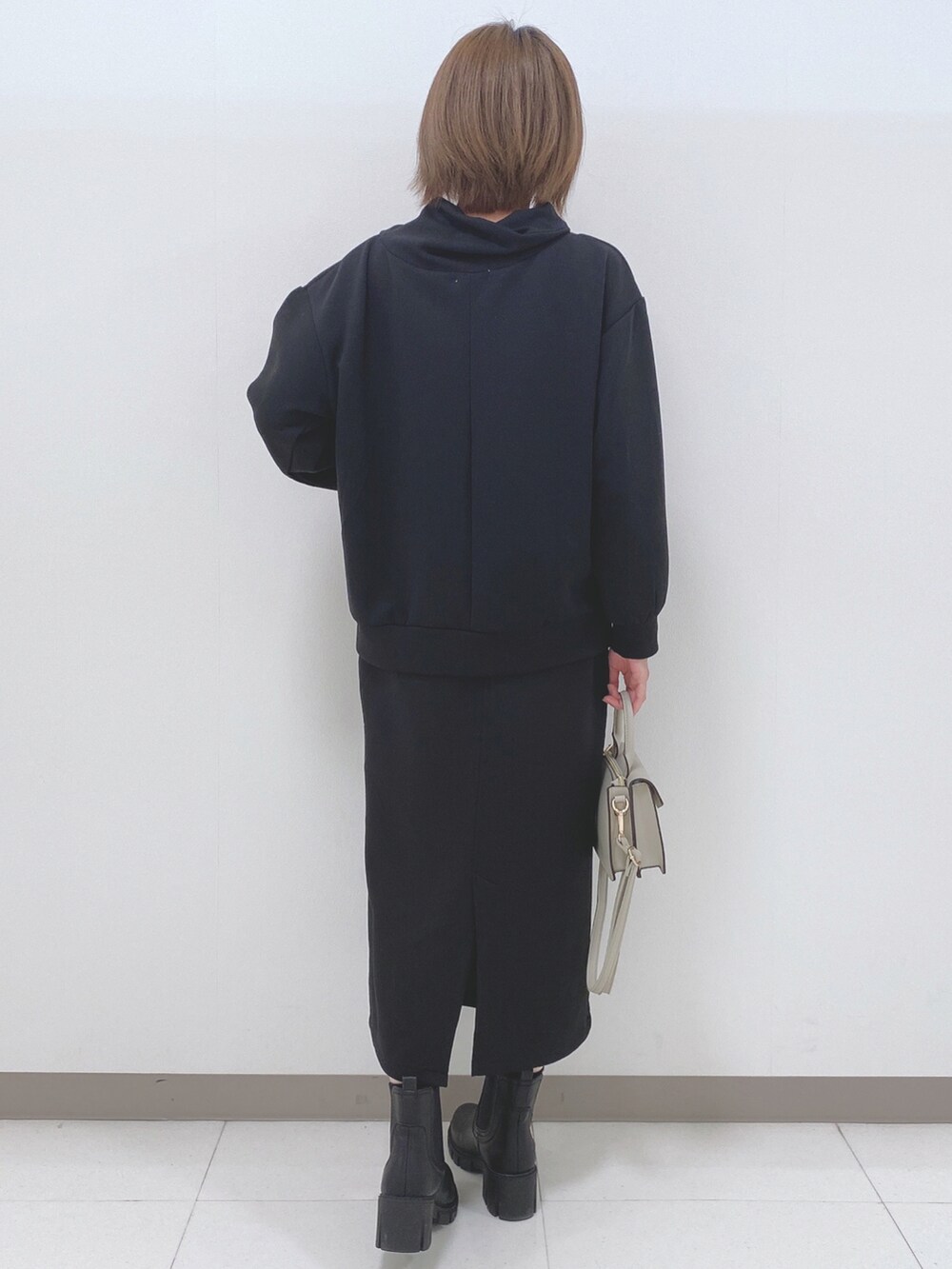 ブラック系のパーカー、ブラック系のスカート、ブラック系のブーツを着用したレディースの秋コーディネートの3枚目の写真