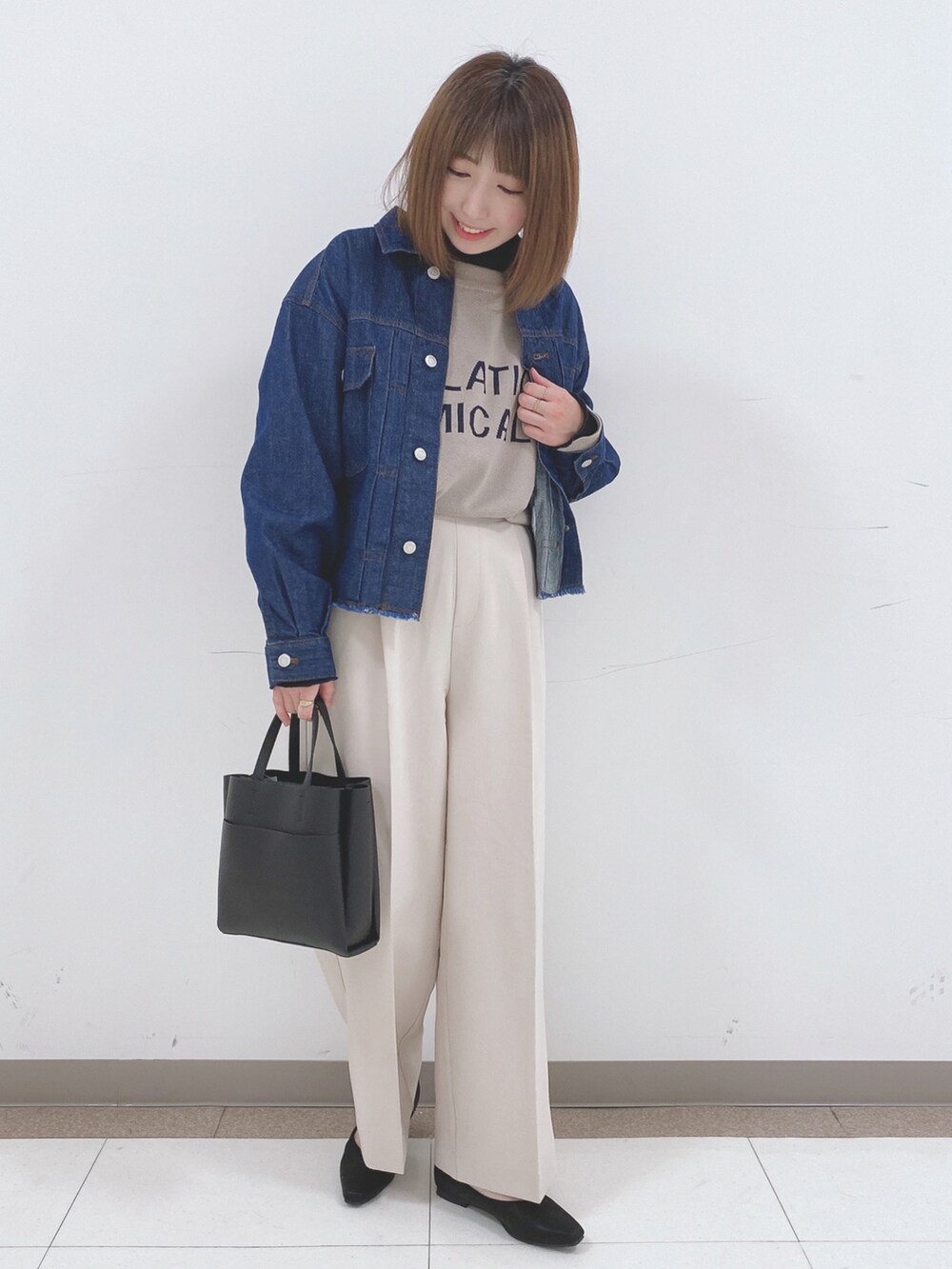 ブルー系のデニムジャケット、ベージュ系のニット/セーター、ベージュ系のその他パンツを着用したレディースの春コーディネートの4枚目の写真