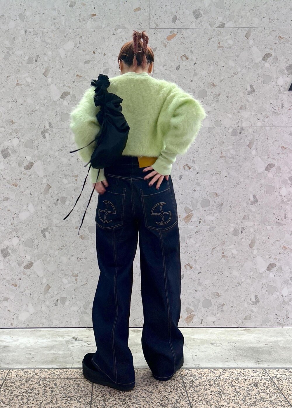 グリーン系のニット/セーター、ブルー系のデニムパンツを着用したレディースの秋コーディネートの4枚目の写真