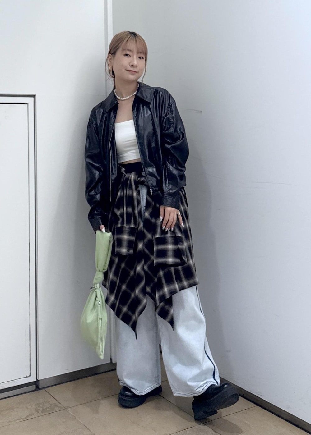 ブルー系のデニムパンツ、ブラック系のサンダル、グリーン系のハンドバッグを着用したレディースの秋コーディネートの2枚目の写真