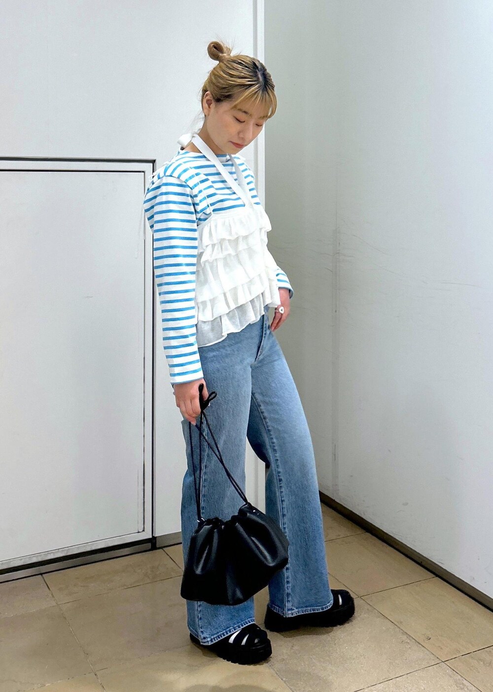 ホワイト系のキャミソール、ブルー系のデニムパンツ、ブラック系のサンダルを着用したレディースの春コーディネートの3枚目の写真