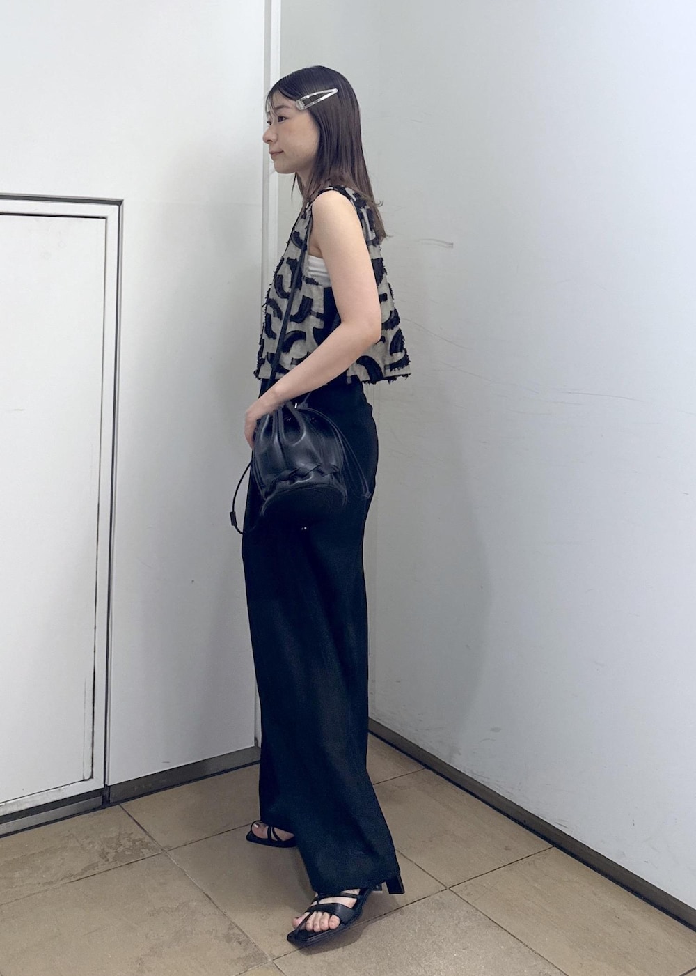 ブラック系のショルダーバッグ、ブラック系のサンダル、ブラック系のスラックスを着用したレディースの夏コーディネートの4枚目の写真
